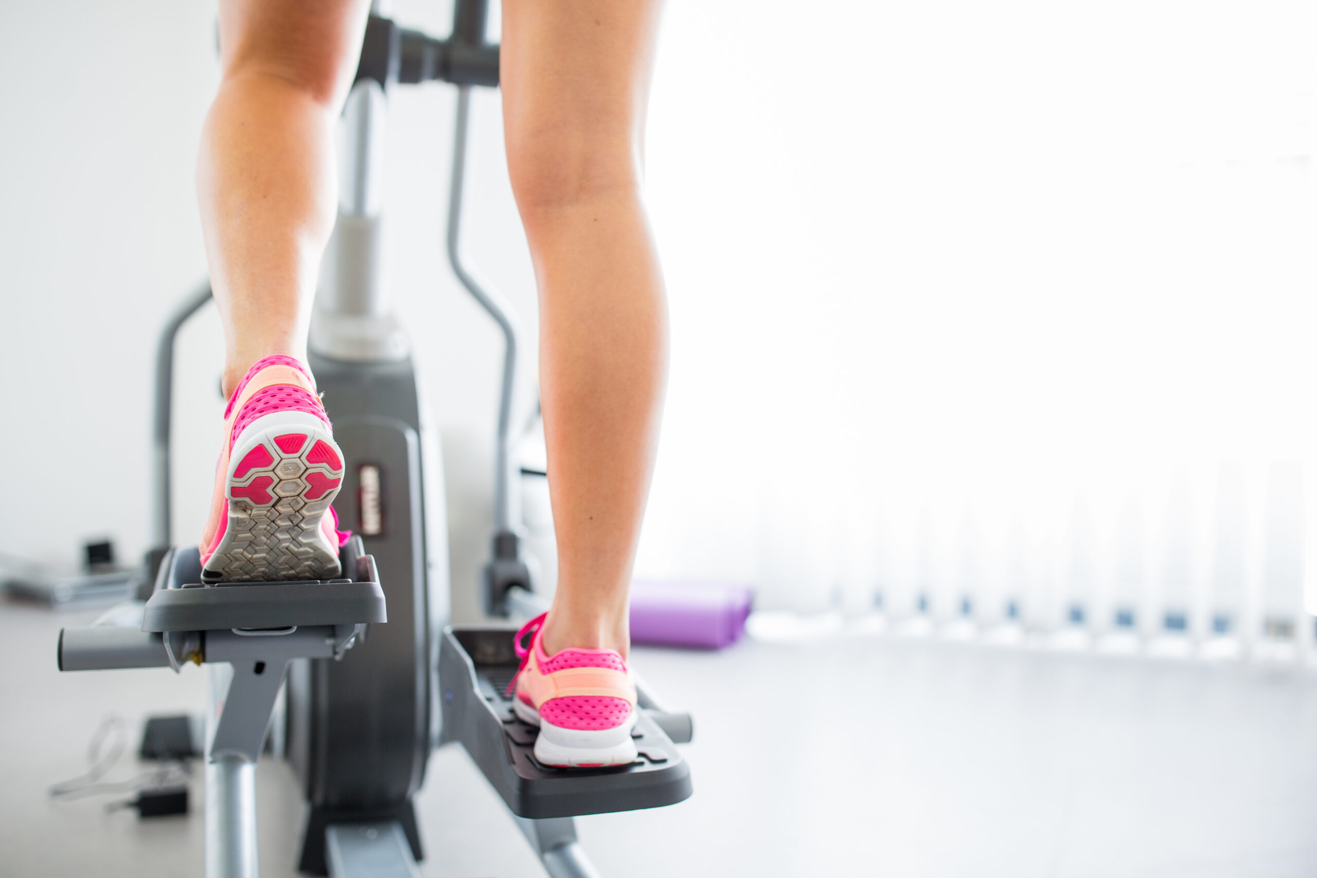Young woman's muscular legs on stepper/treadmill, closeup